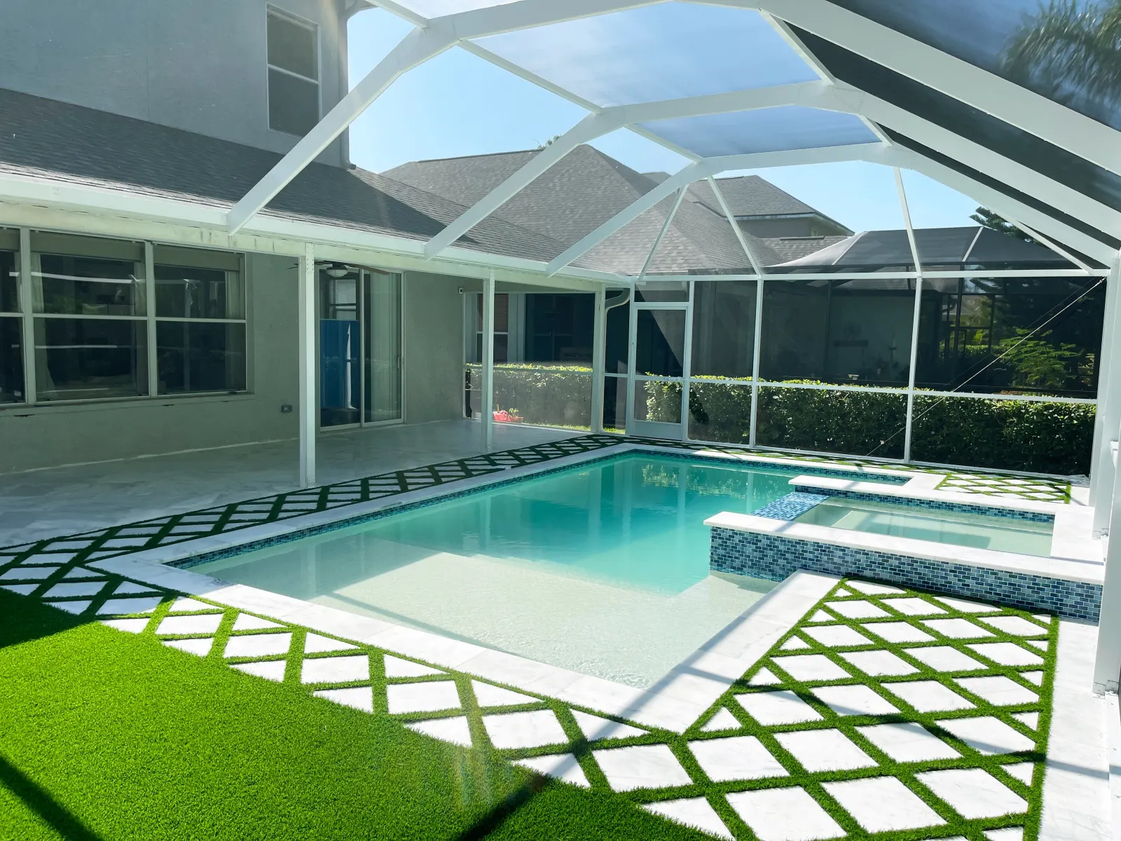 Screened lanai pool with a checkerboard paver deck pattern.